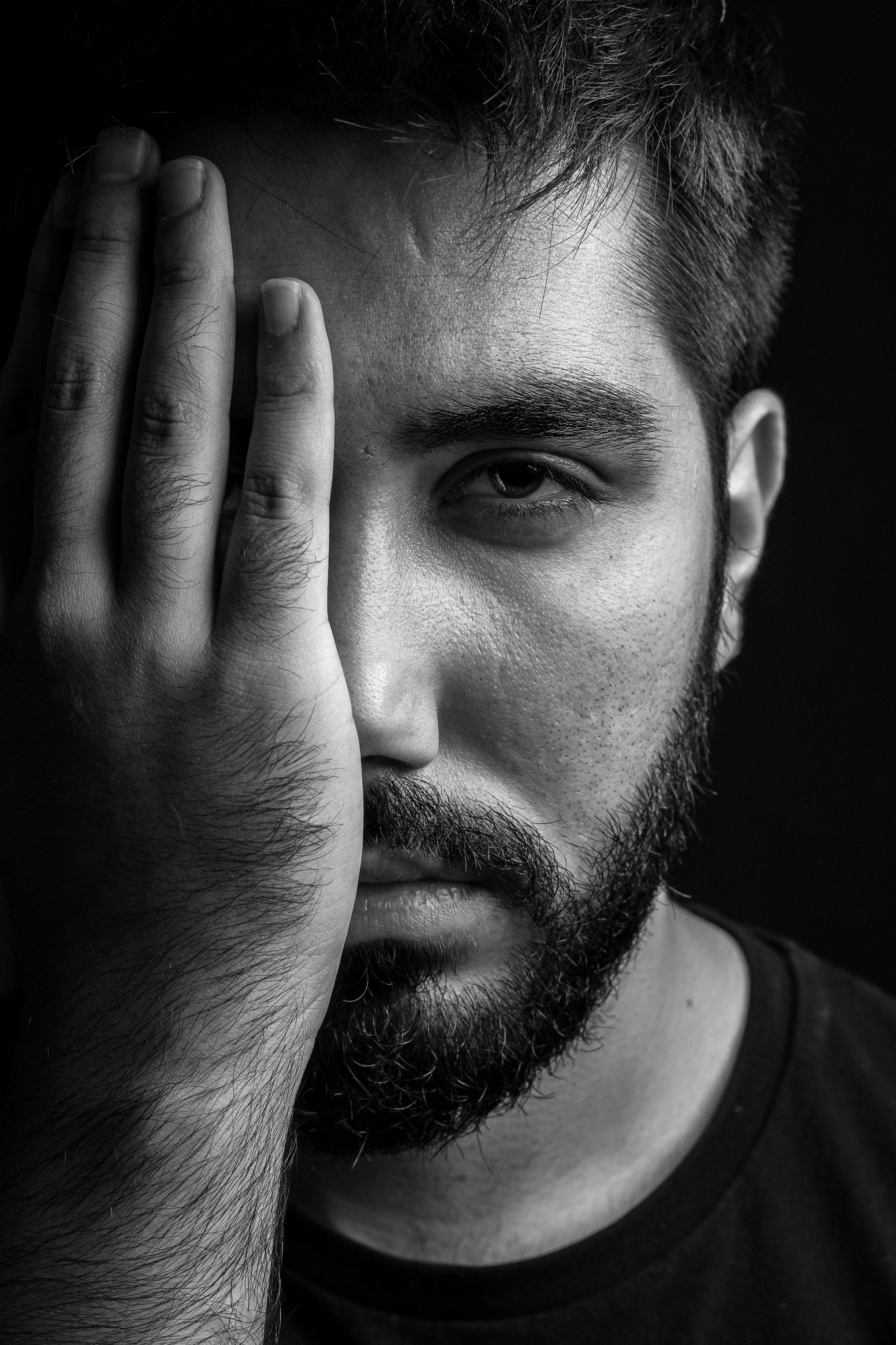 man in crew neck shirt covering his face